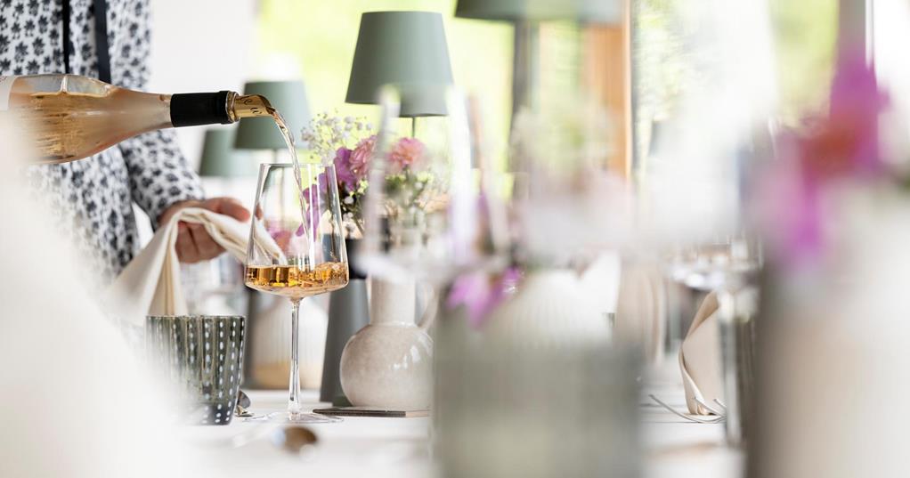 A woman serves a glass of wine